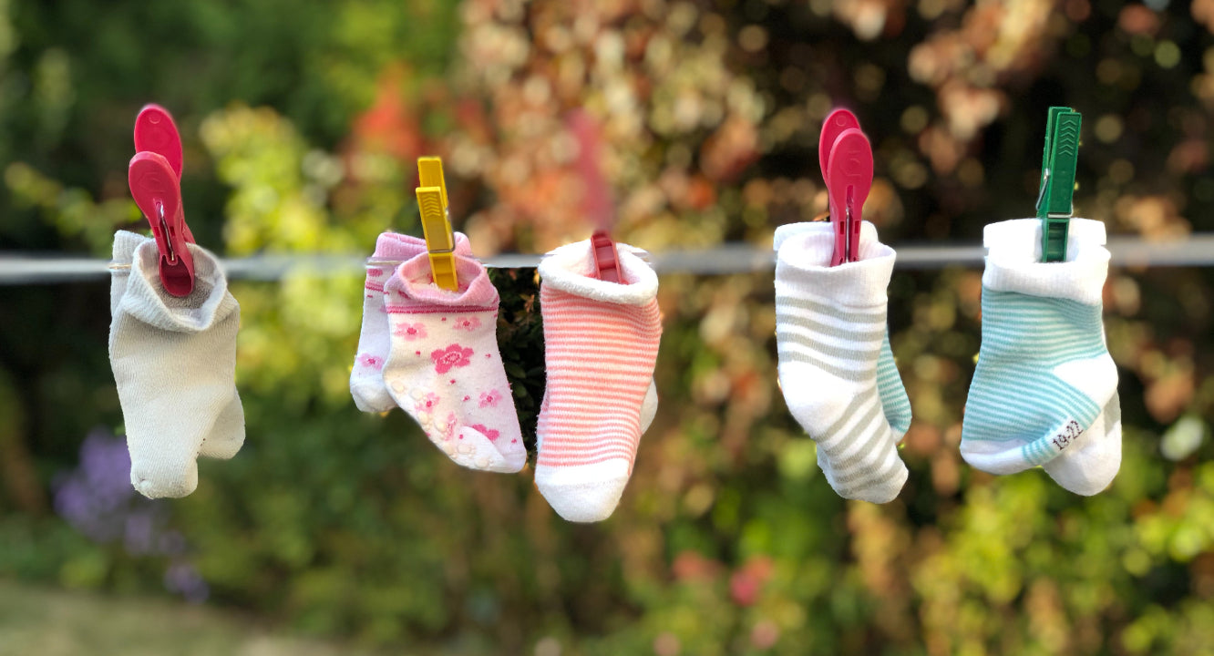 Page d'accueil du site Bébou. Une image de chaussettes pour bébés accroché à une corde à linges.